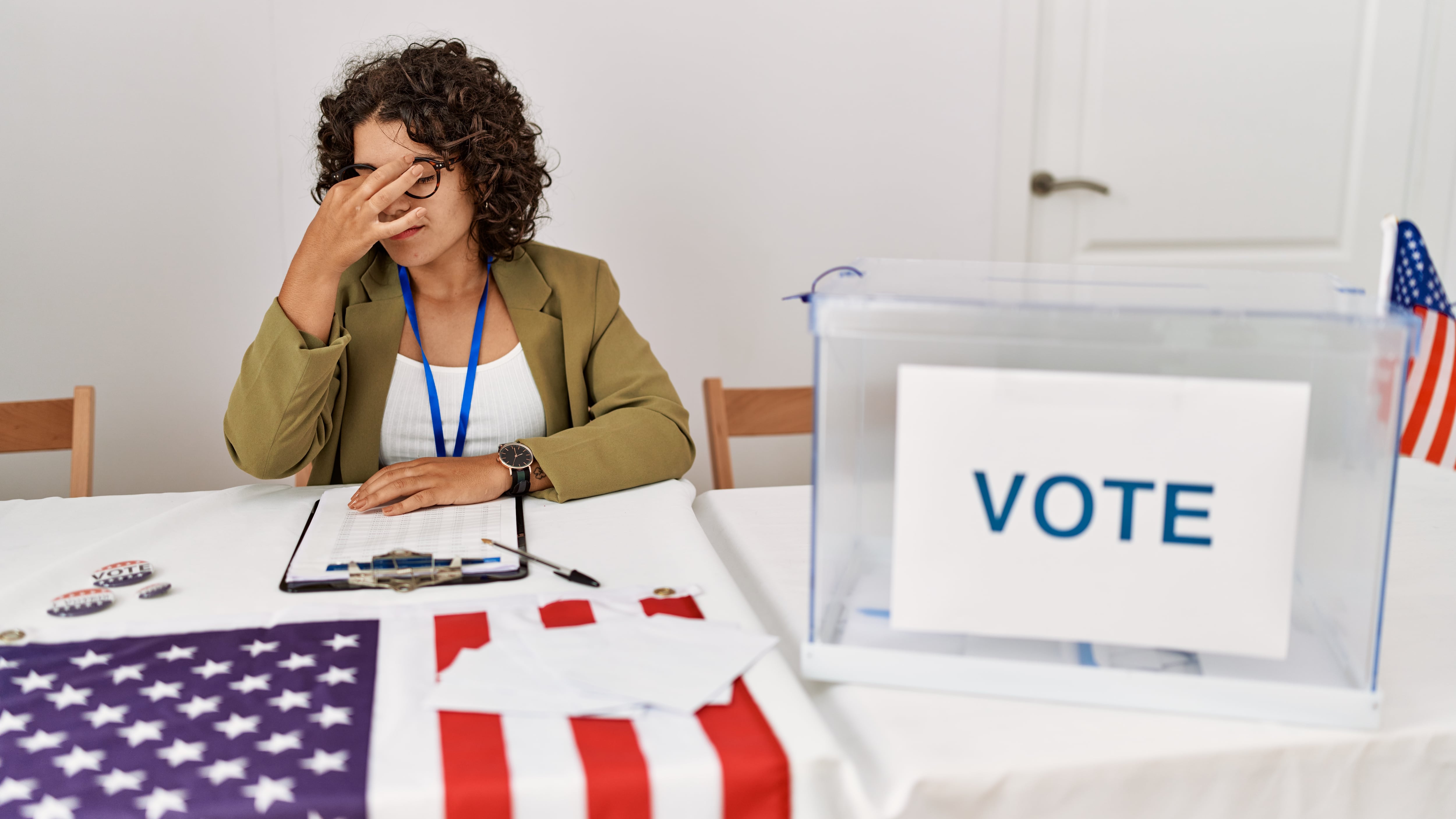 Young hispanic woman at political election sitting by ballot tired rubbing nose and eyes feeling fatigue and headache. stress and frustration concept.
